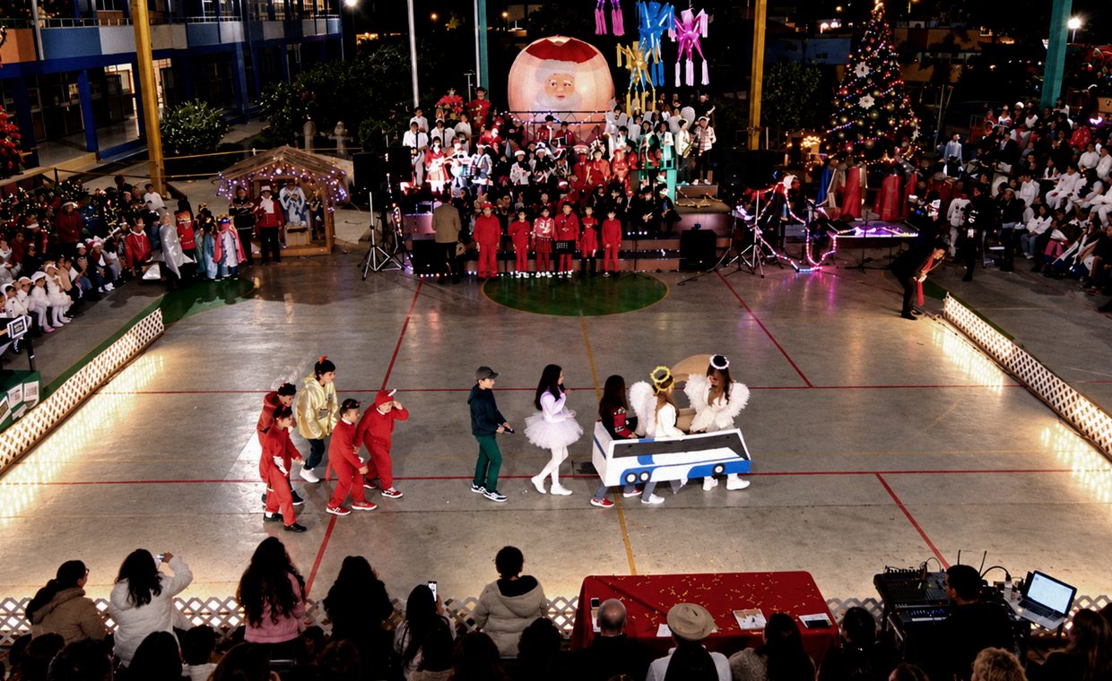 Evento navideño en un auditorio con escenario iluminado y público