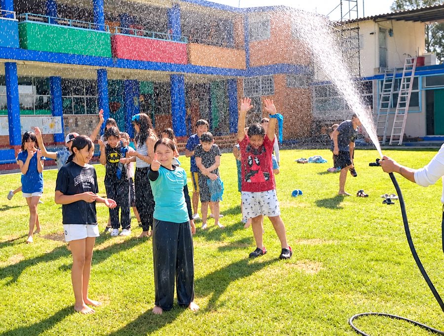 Niños en el área verde jugando con agua bajo un estructura de red